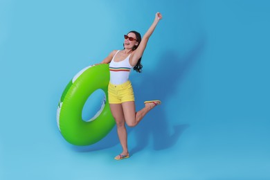 Photo of Beautiful woman in swimsuit with inflatable ring on light blue background