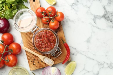 Photo of Spicy salsa and ingredients on white marble table, flat lay. Space for text