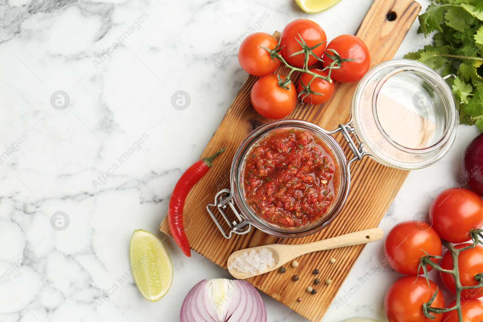 Photo of Spicy salsa and ingredients on white marble table, flat lay. Space for text