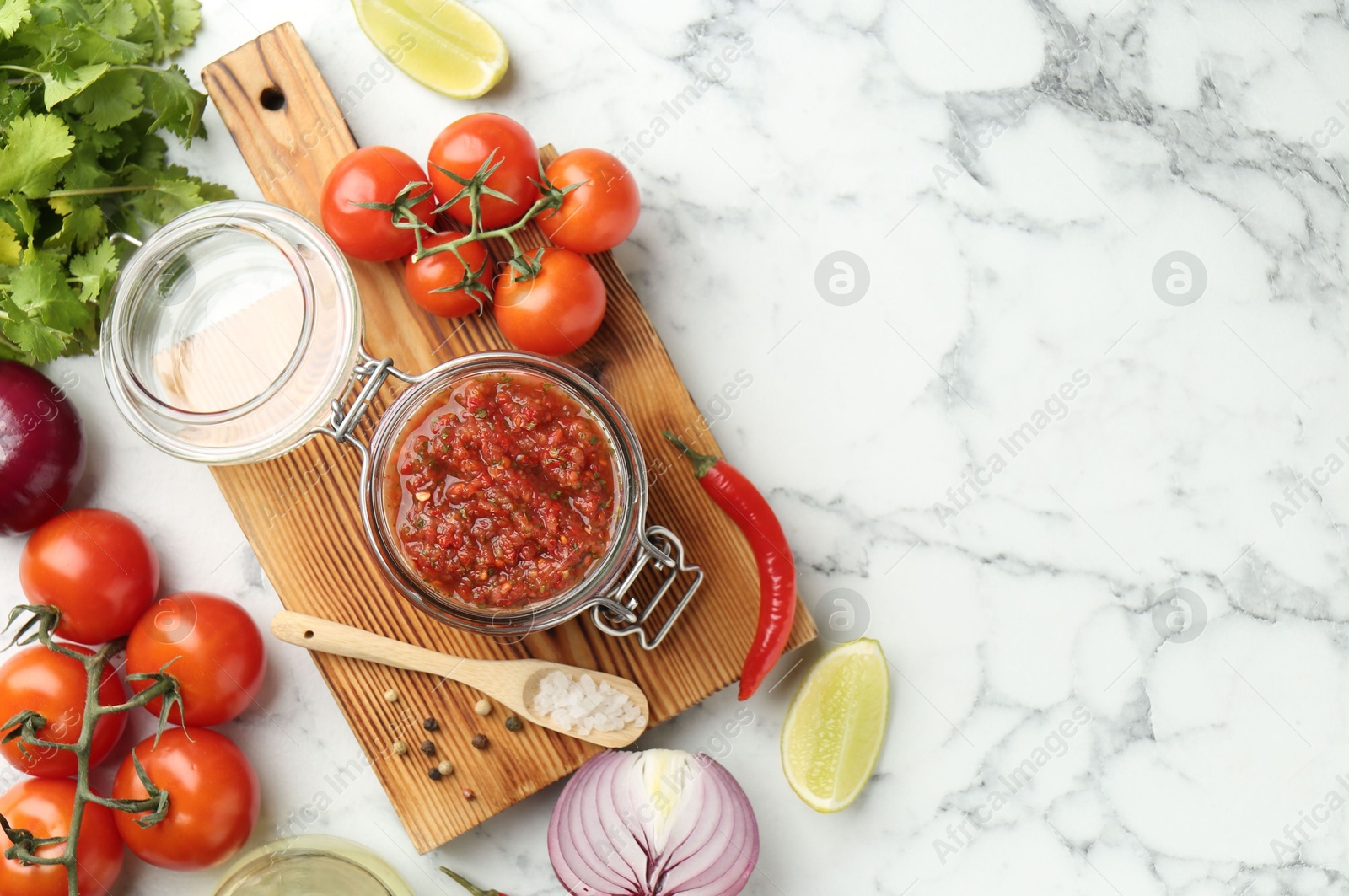 Photo of Spicy salsa and ingredients on white marble table, flat lay. Space for text