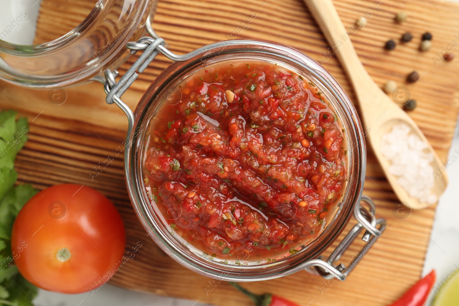 Photo of Spicy salsa and ingredients on white table, top view