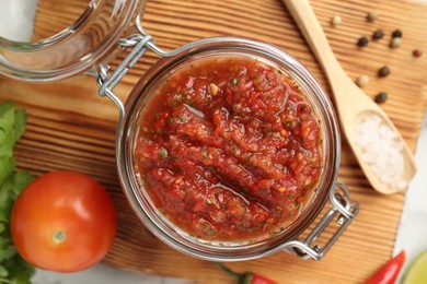 Photo of Spicy salsa and ingredients on white table, top view