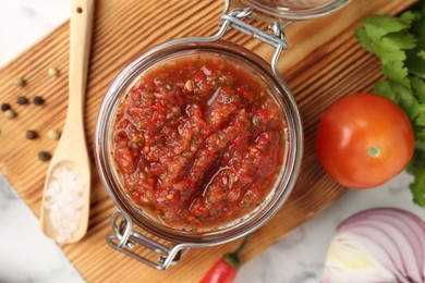 Photo of Spicy salsa and ingredients on white table, top view