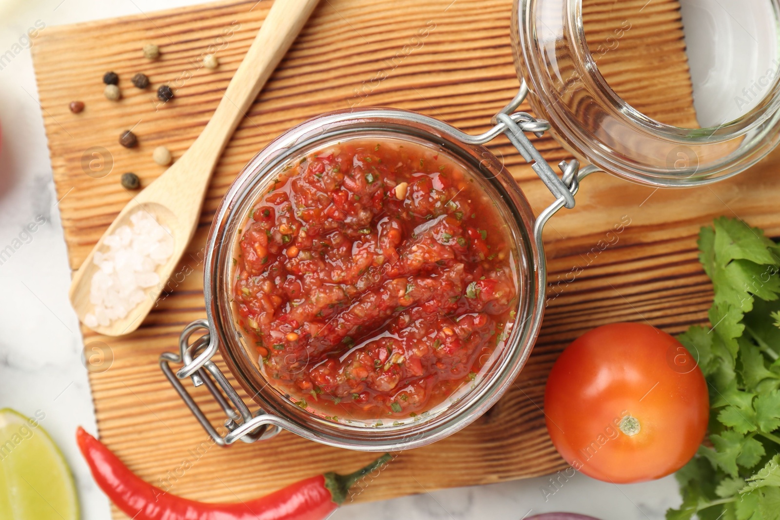 Photo of Spicy salsa and ingredients on white table, top view