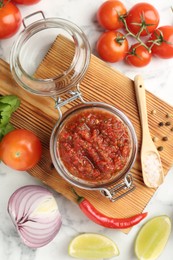 Photo of Spicy salsa and ingredients on white marble table, flat lay