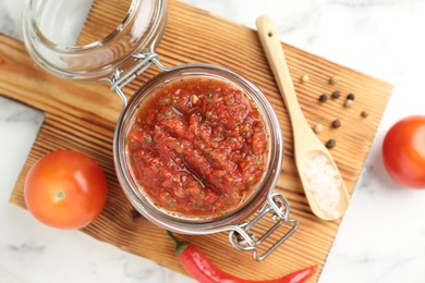 Photo of Spicy salsa and ingredients on white table, top view