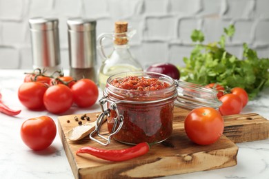 Photo of Spicy salsa and ingredients on white table