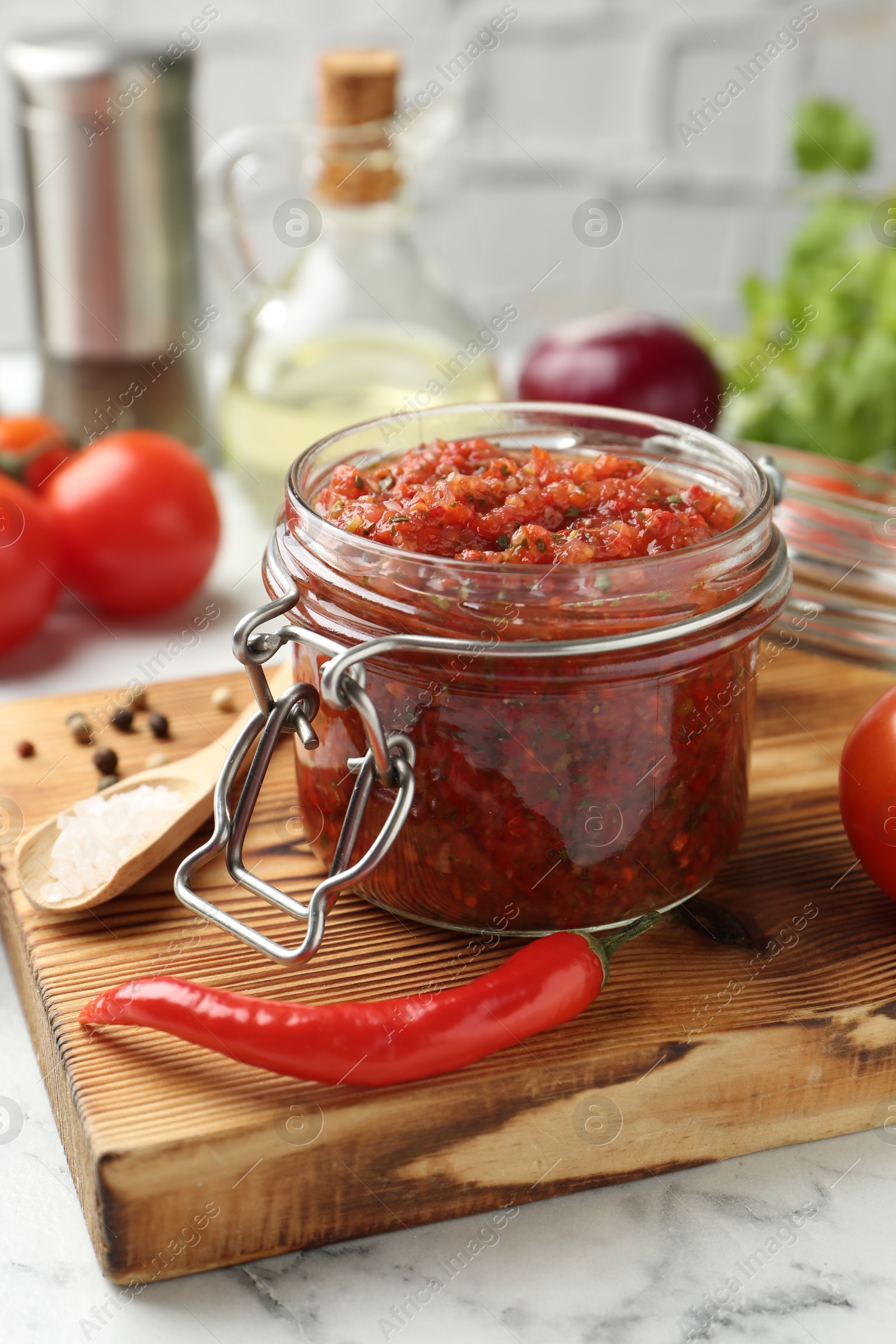 Photo of Spicy salsa and ingredients on white table