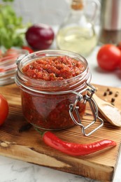 Photo of Spicy salsa and ingredients on white table