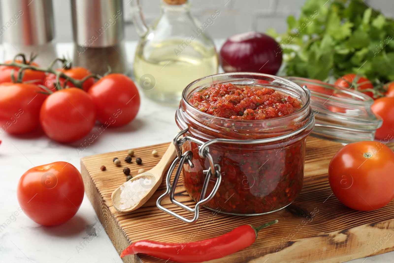 Photo of Spicy salsa and ingredients on white table