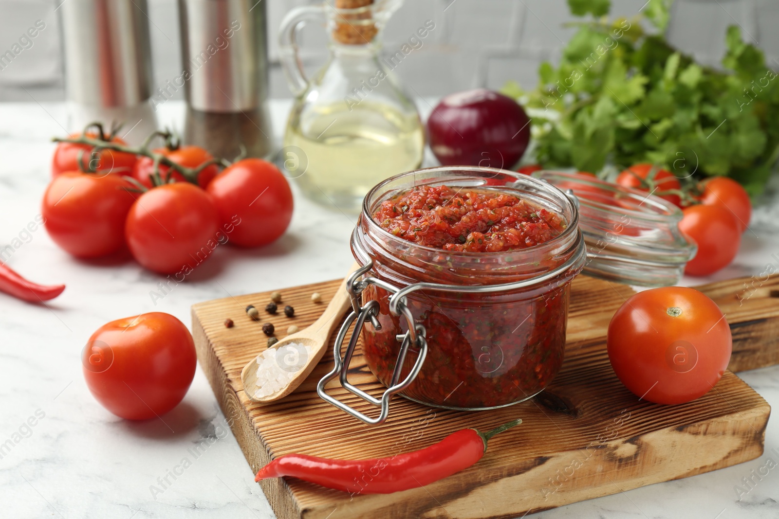 Photo of Spicy salsa and ingredients on white table