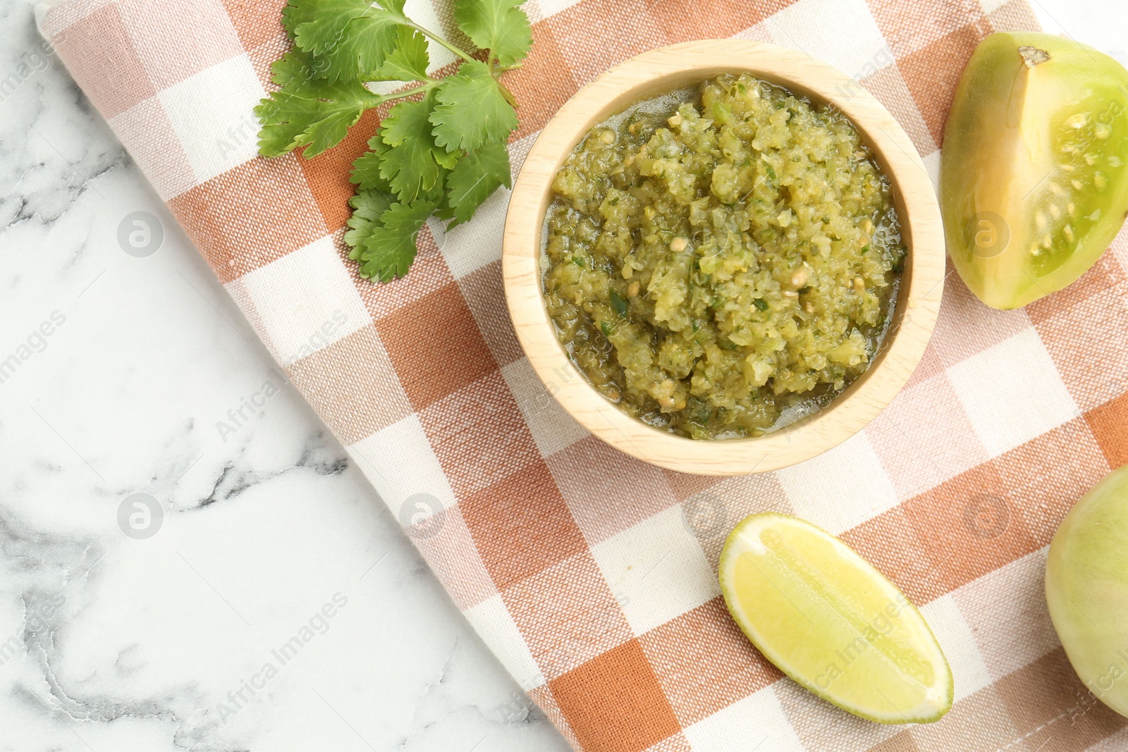 Photo of Spicy salsa and ingredients on white marble table, flat lay