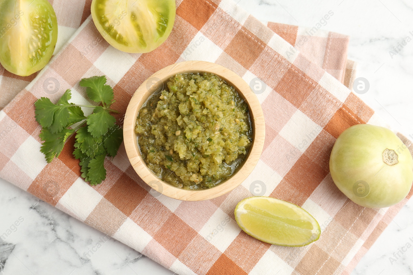 Photo of Spicy salsa and ingredients on white marble table, flat lay