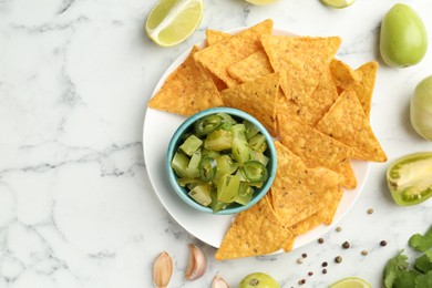 Photo of Delicious salsa with nachos on white marble table, flat lay