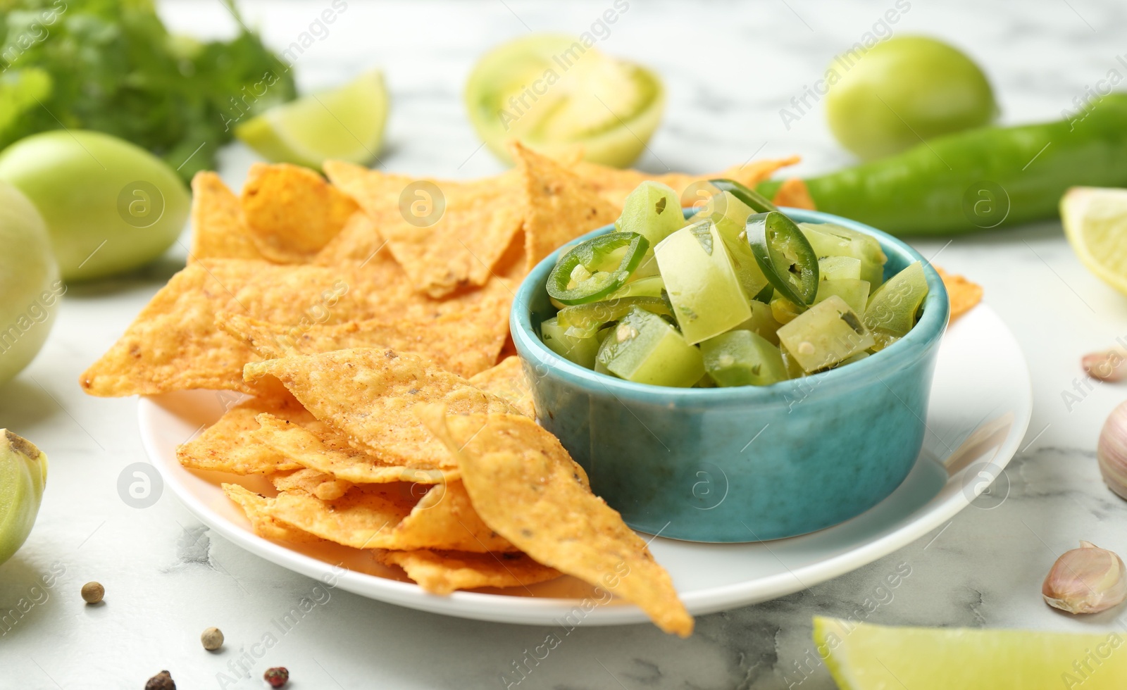 Photo of Delicious salsa with nachos on white table, closeup