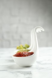 Photo of Sauce boats with salsa on white marble table, selective focus. Space for text