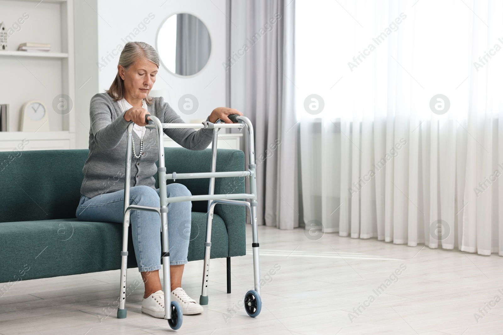 Photo of Senior woman with walking frame on sofa at home, space for text