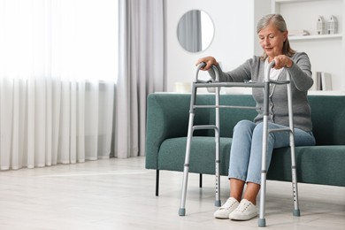 Photo of Senior woman with walking frame on sofa at home, space for text