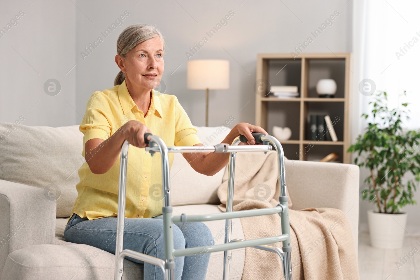 Photo of Senior woman with walking frame on sofa at home