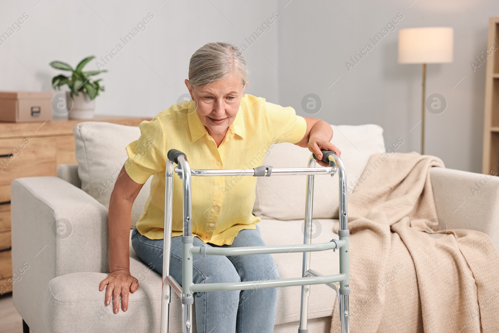 Photo of Senior woman with walking frame on sofa at home