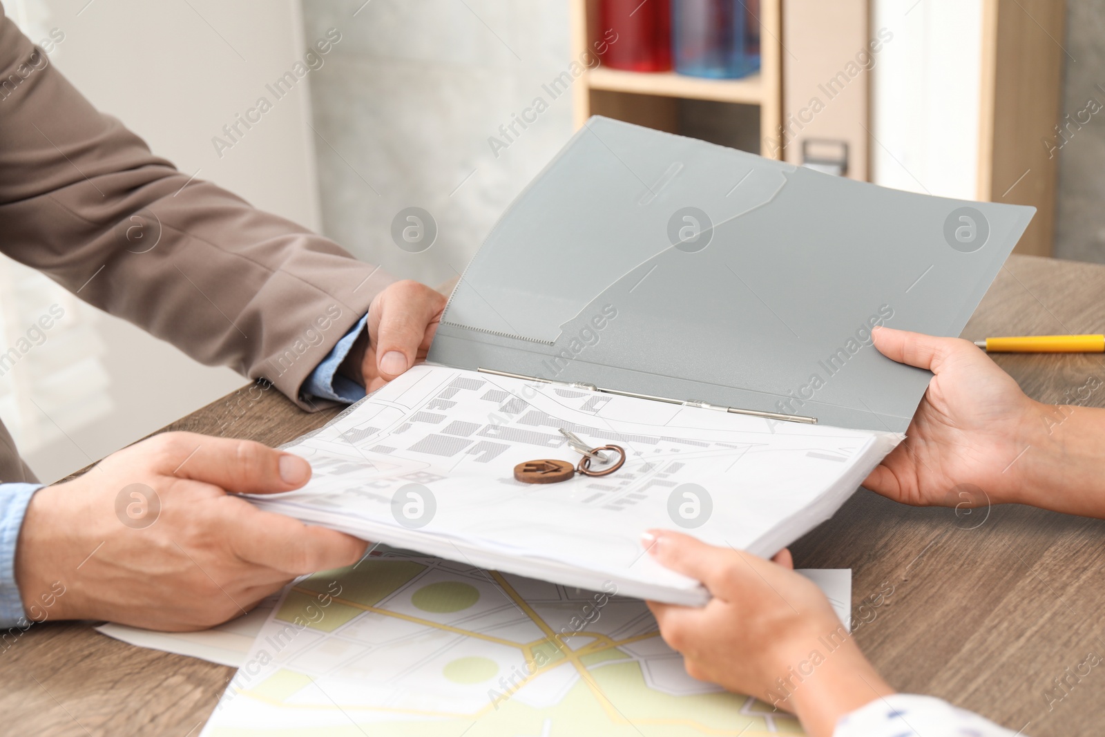 Photo of Real estate agent working with client at wooden table, closeup