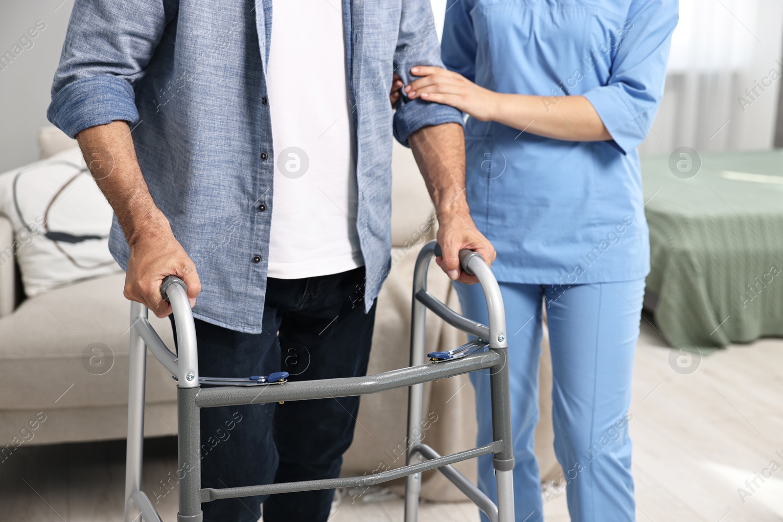 Photo of Nurse helping senior man with walking frame indoors, closeup