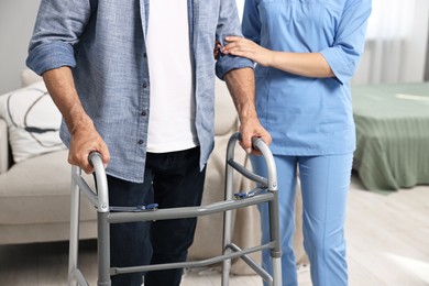 Photo of Nurse helping senior man with walking frame indoors, closeup