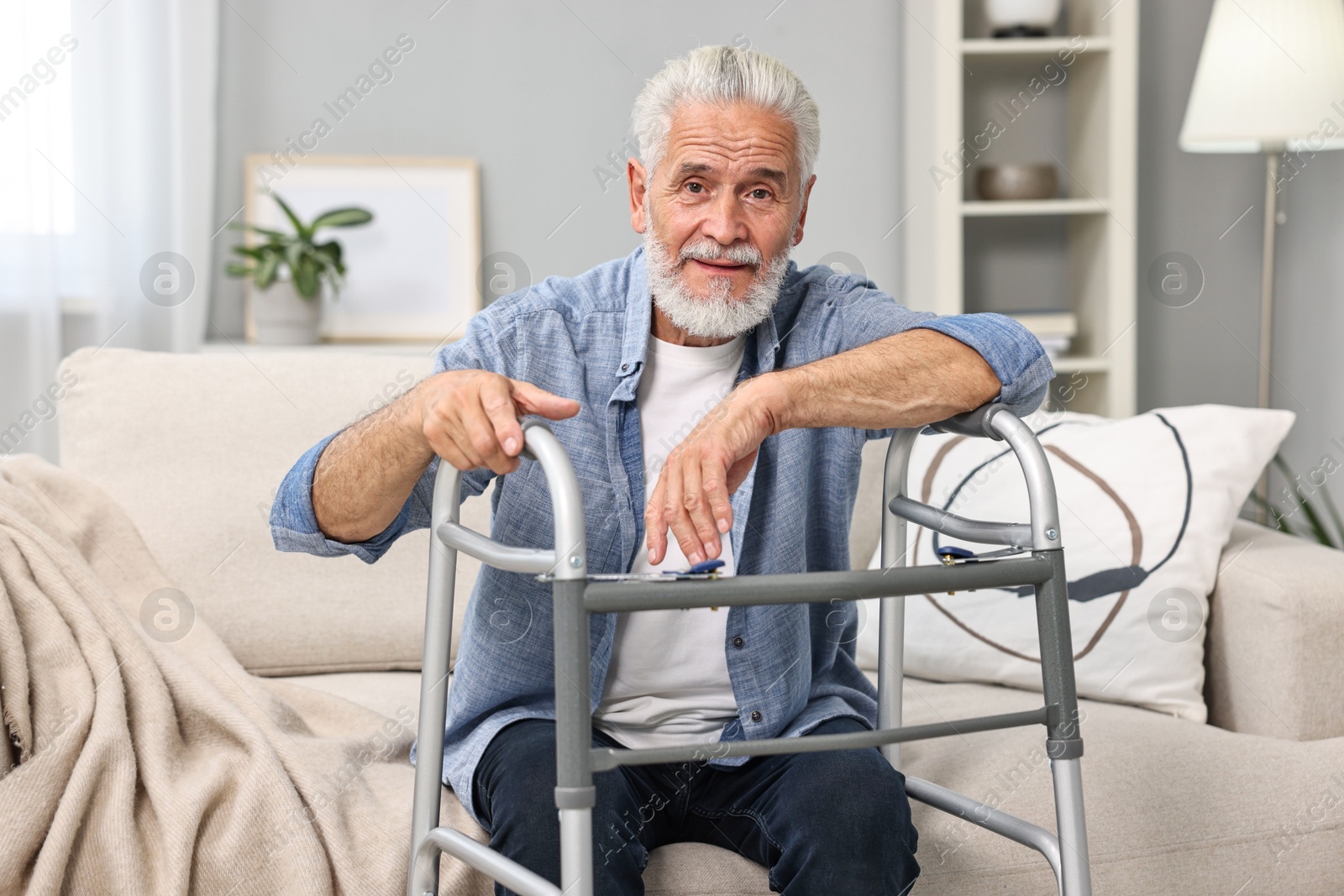 Photo of Senior man with walking frame on sofa at home