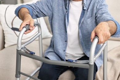 Photo of Senior man with walking frame on sofa at home, closeup