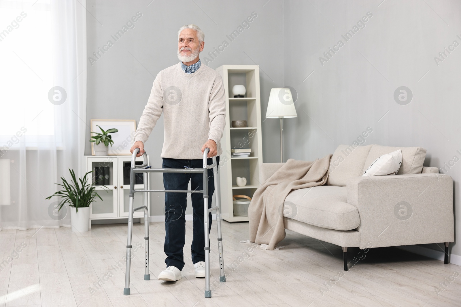 Photo of Senior man using walking frame at home