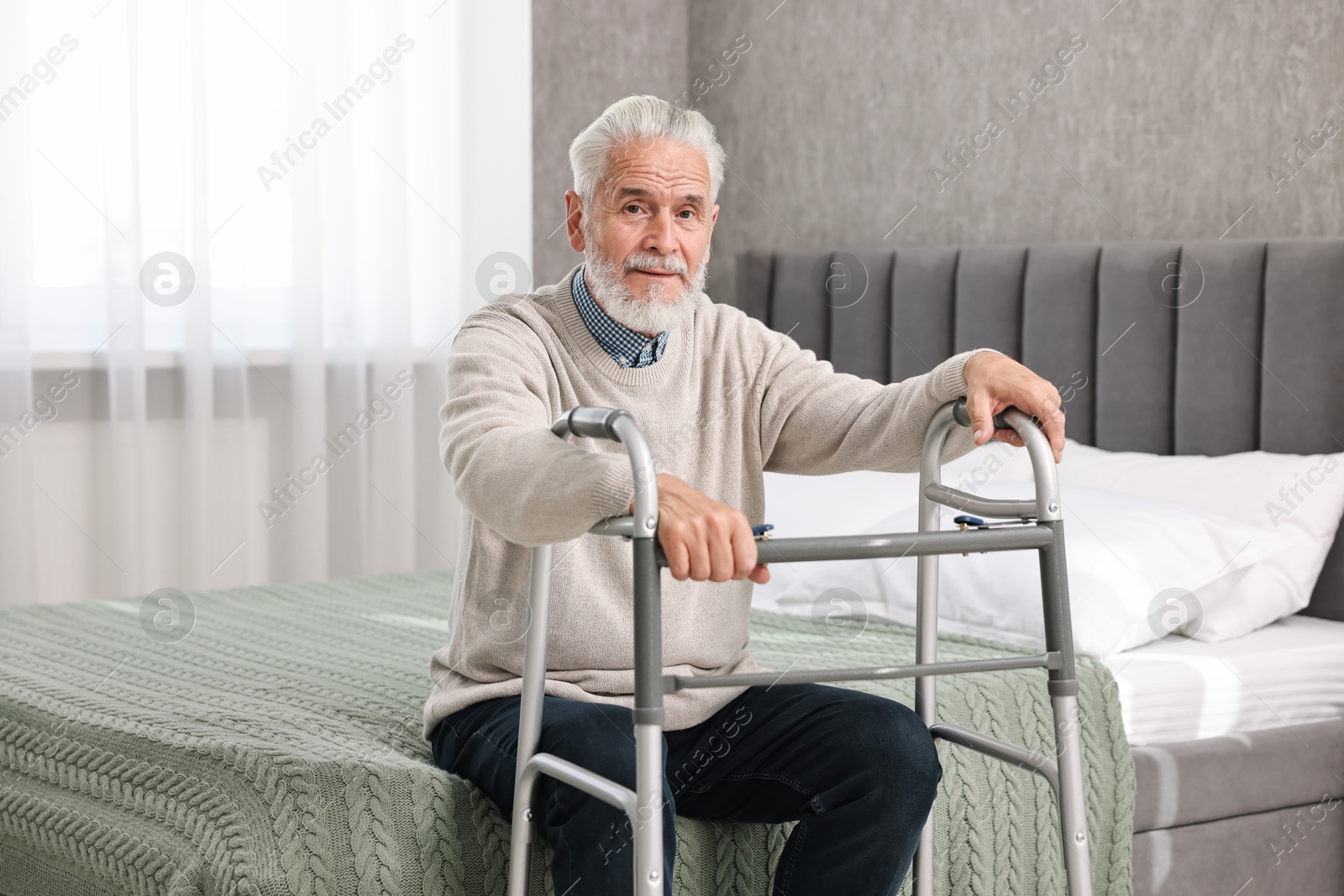 Photo of Senior man with walking frame on bed at home