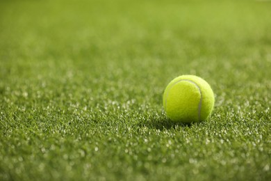 Tennis ball on green artificial grass, space for text