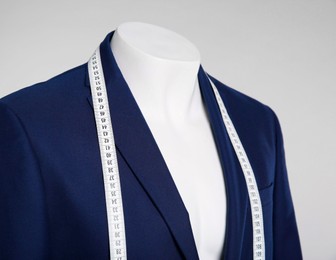 Photo of Male mannequin with elegant suit jacket and measuring tape on grey background, closeup