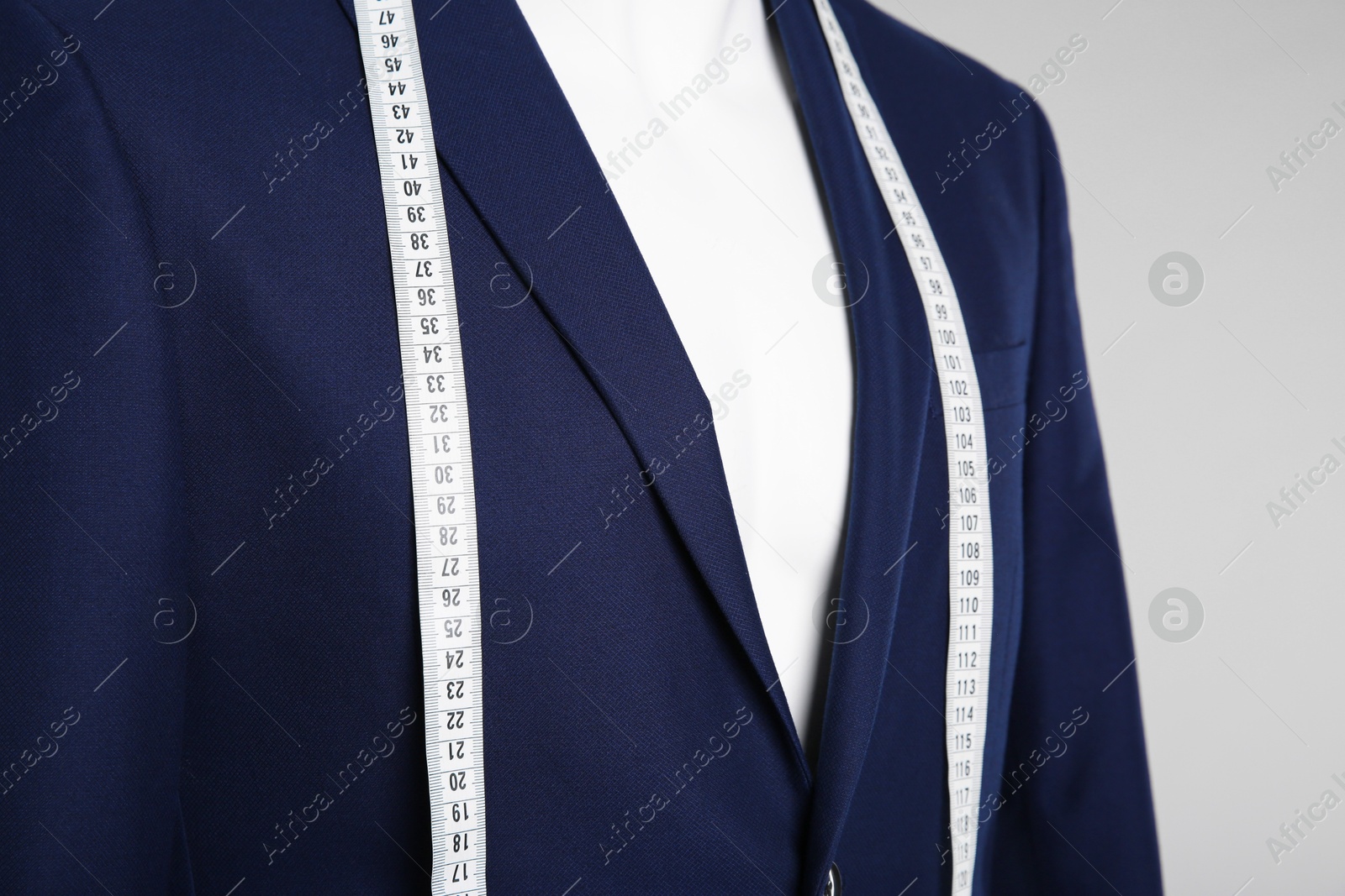 Photo of Male mannequin with elegant suit jacket and measuring tape on grey background, closeup