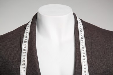 Photo of Male mannequin with elegant suit jacket and measuring tape on grey background, closeup