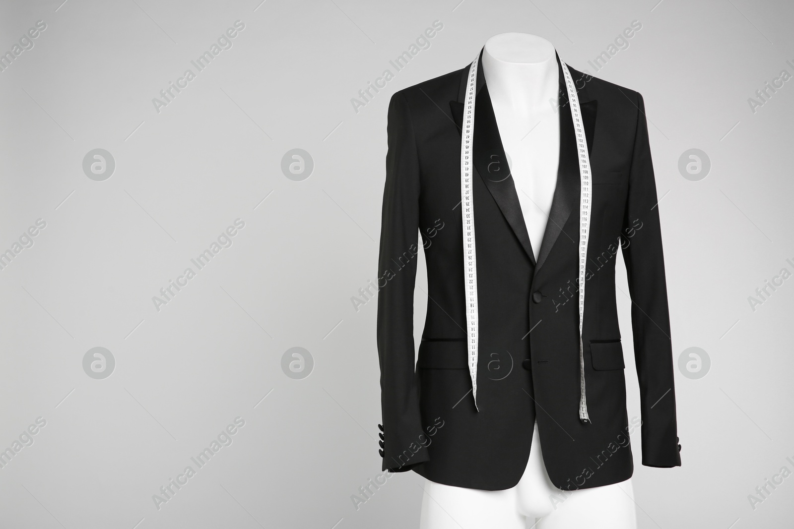 Photo of Male mannequin with elegant suit jacket and measuring tape on grey background. Space for text