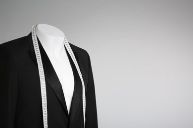 Photo of Male mannequin with elegant suit jacket and measuring tape on grey background. Space for text