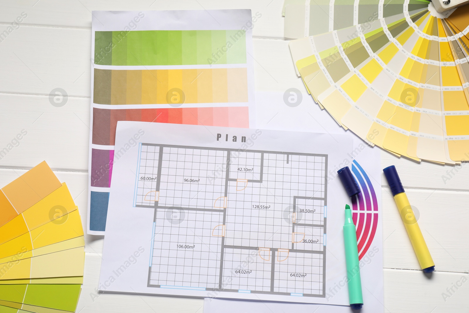 Photo of Designer's workplace with color palettes, floor plan and stationery on white wooden table, flat lay