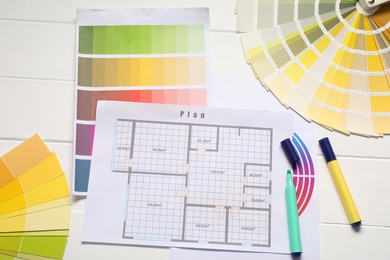 Photo of Designer's workplace with color palettes, floor plan and stationery on white wooden table, flat lay