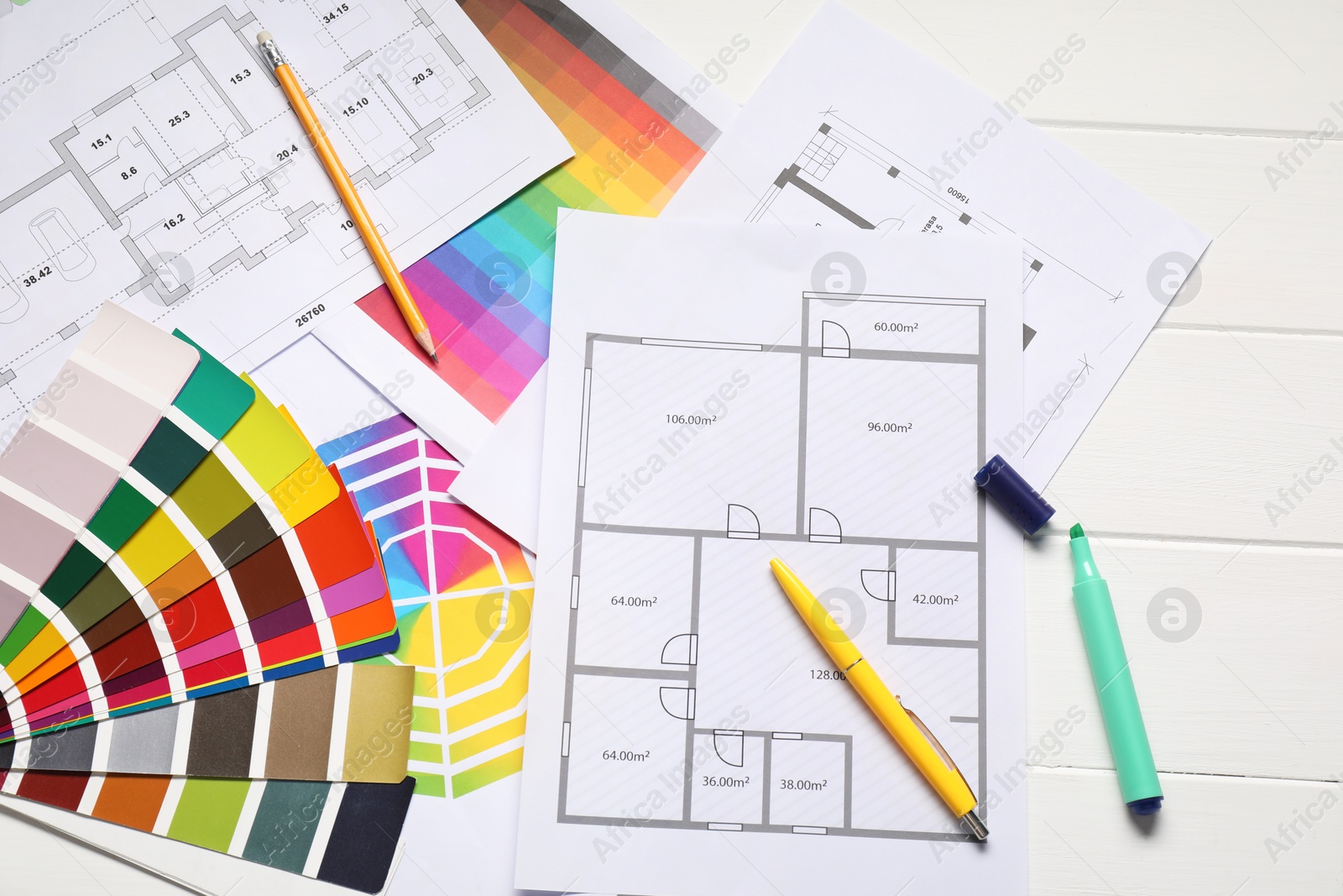 Photo of Designer's workplace with color palettes, floor plans and stationery on white wooden table, flat lay