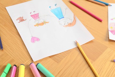 Photo of Child`s picture and stationery on wooden table, closeup