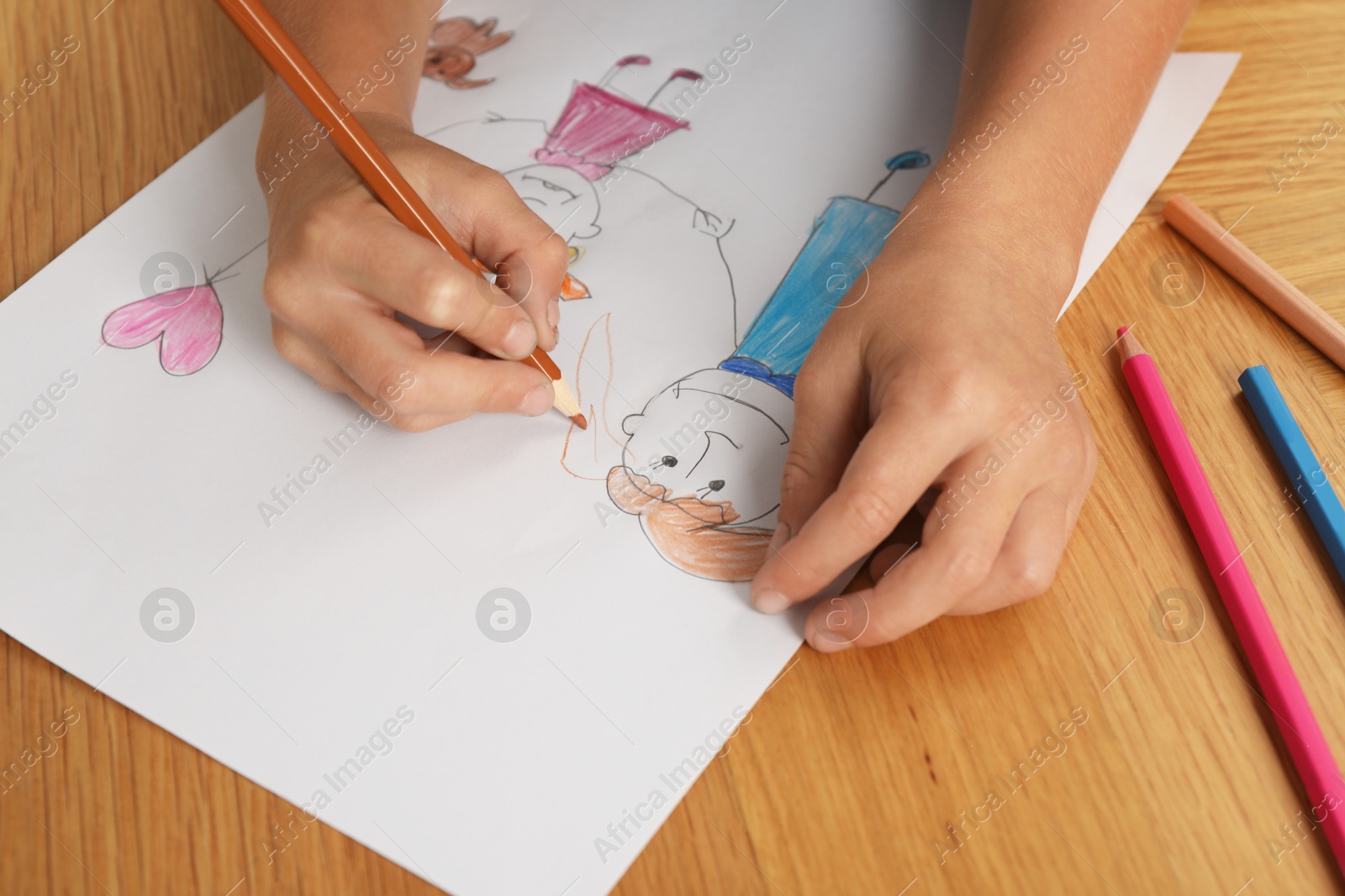 Photo of Boy drawing his family at wooden table, closeup