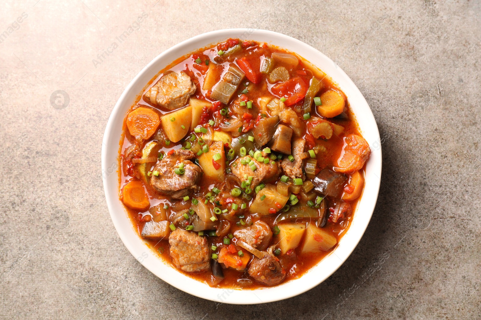 Photo of Delicious stew with vegetables in bowl on light grey table, top view