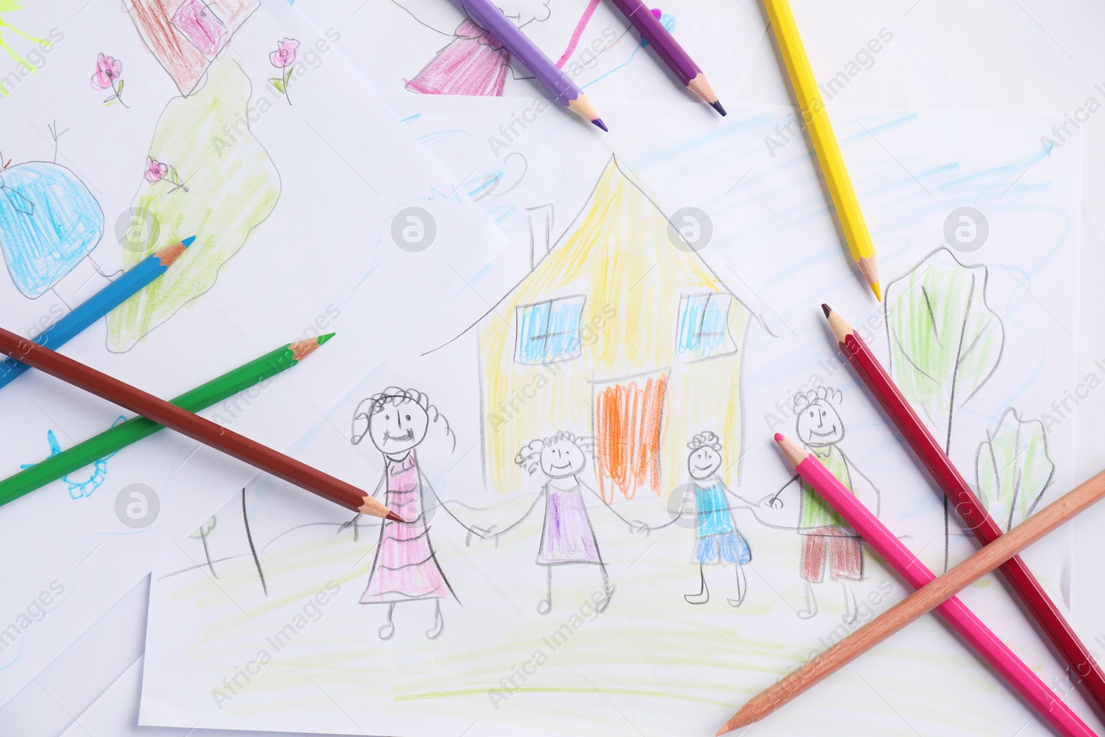 Photo of Child's drawing of happy family and pencils on table, top view