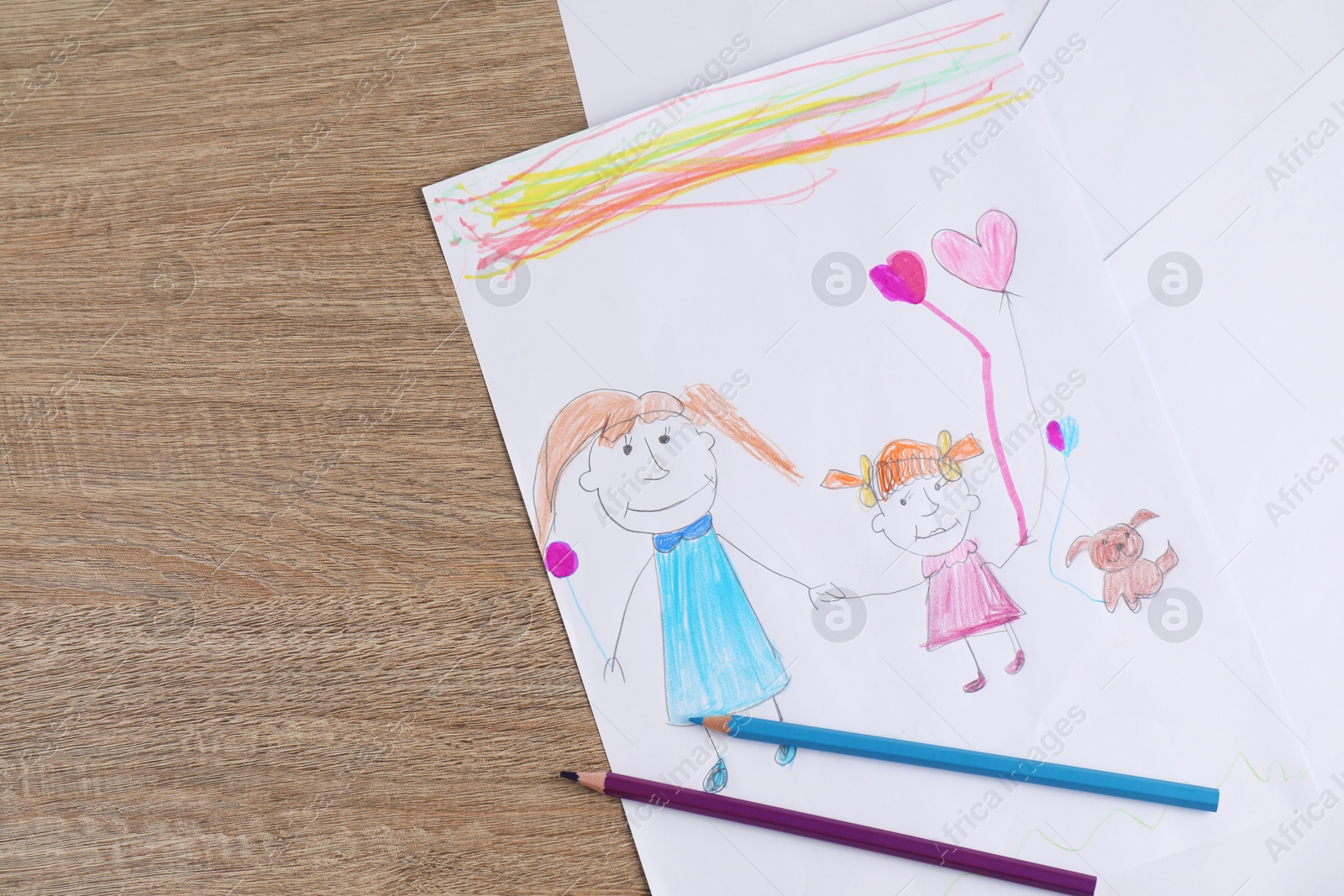 Photo of Child's drawing of happy family and pencils on wooden table, top view