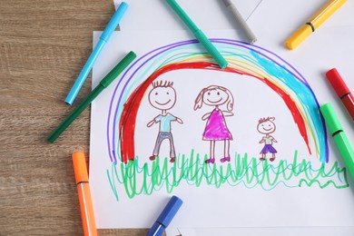 Photo of Child's drawing of happy family and felt tip pens on wooden table, top view