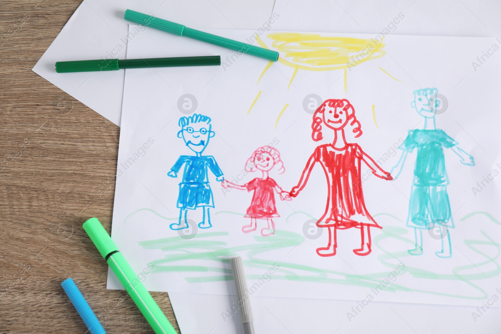 Photo of Child's drawing of happy family and felt tip pens on wooden table, top view