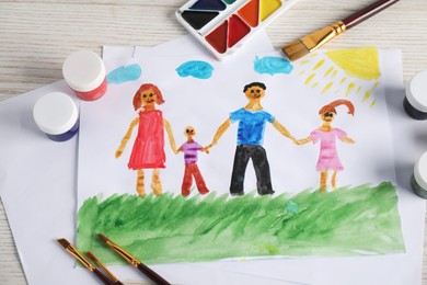 Photo of Child's drawing of happy family and supplies on wooden table, above view