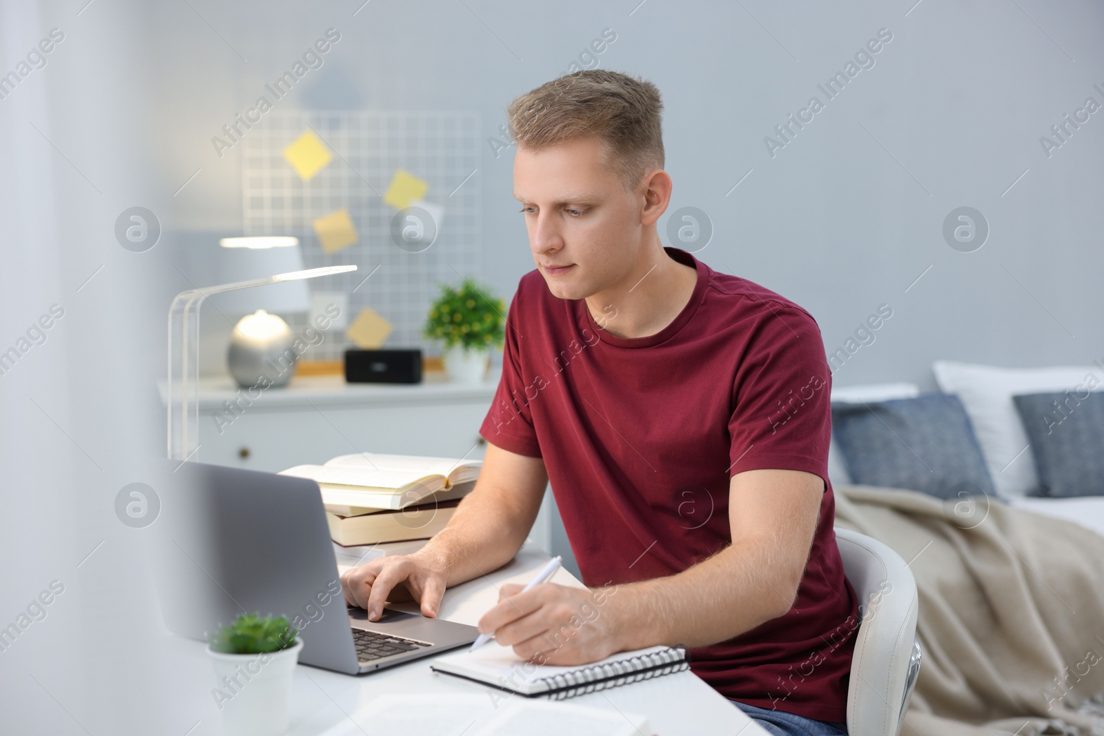 Photo of Student preparing for exam with laptop at table indoors