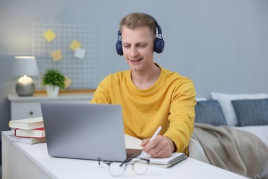 Photo of Student preparing for exam with laptop at table indoors